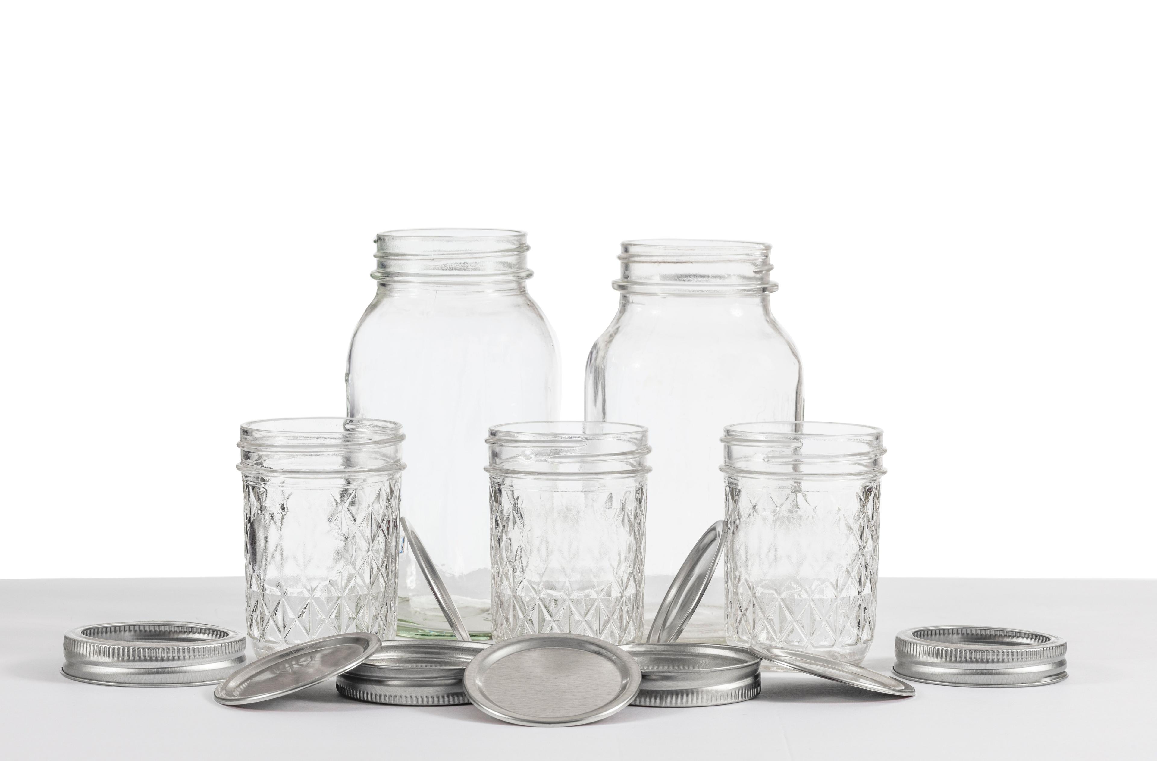 Assorted empty mason jars and glass bottles with lids displayed on white background