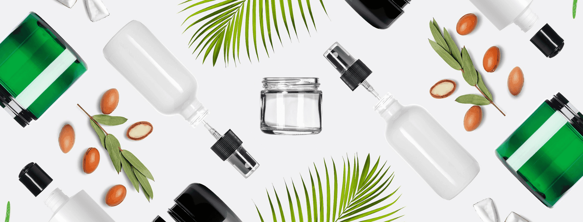 Flat lay of cosmetic glass jars, leaves, and natural product icons over white background